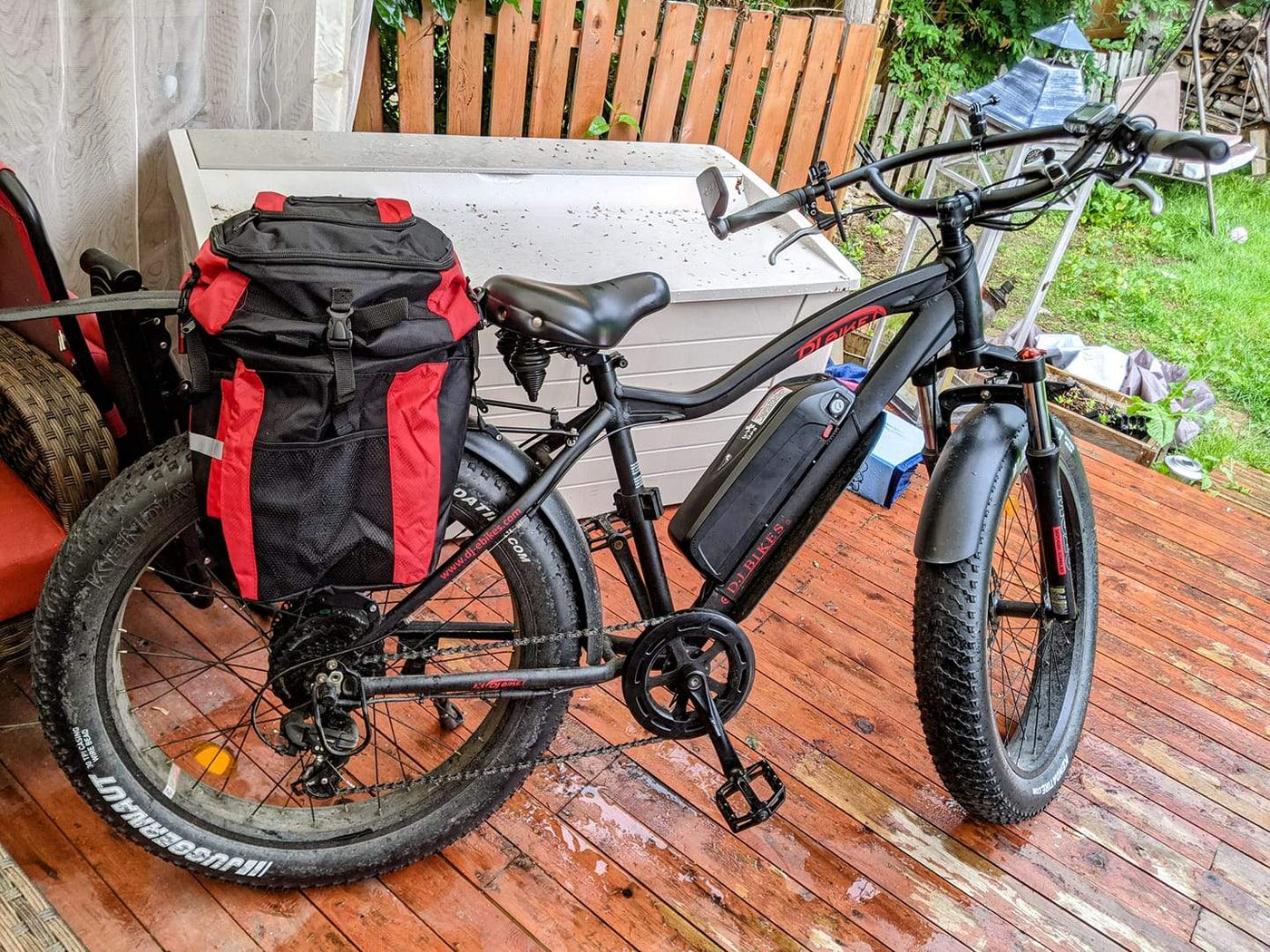 A DJ Fat Bike fat tire e-bike equipped with pannier bag on a wooden deck