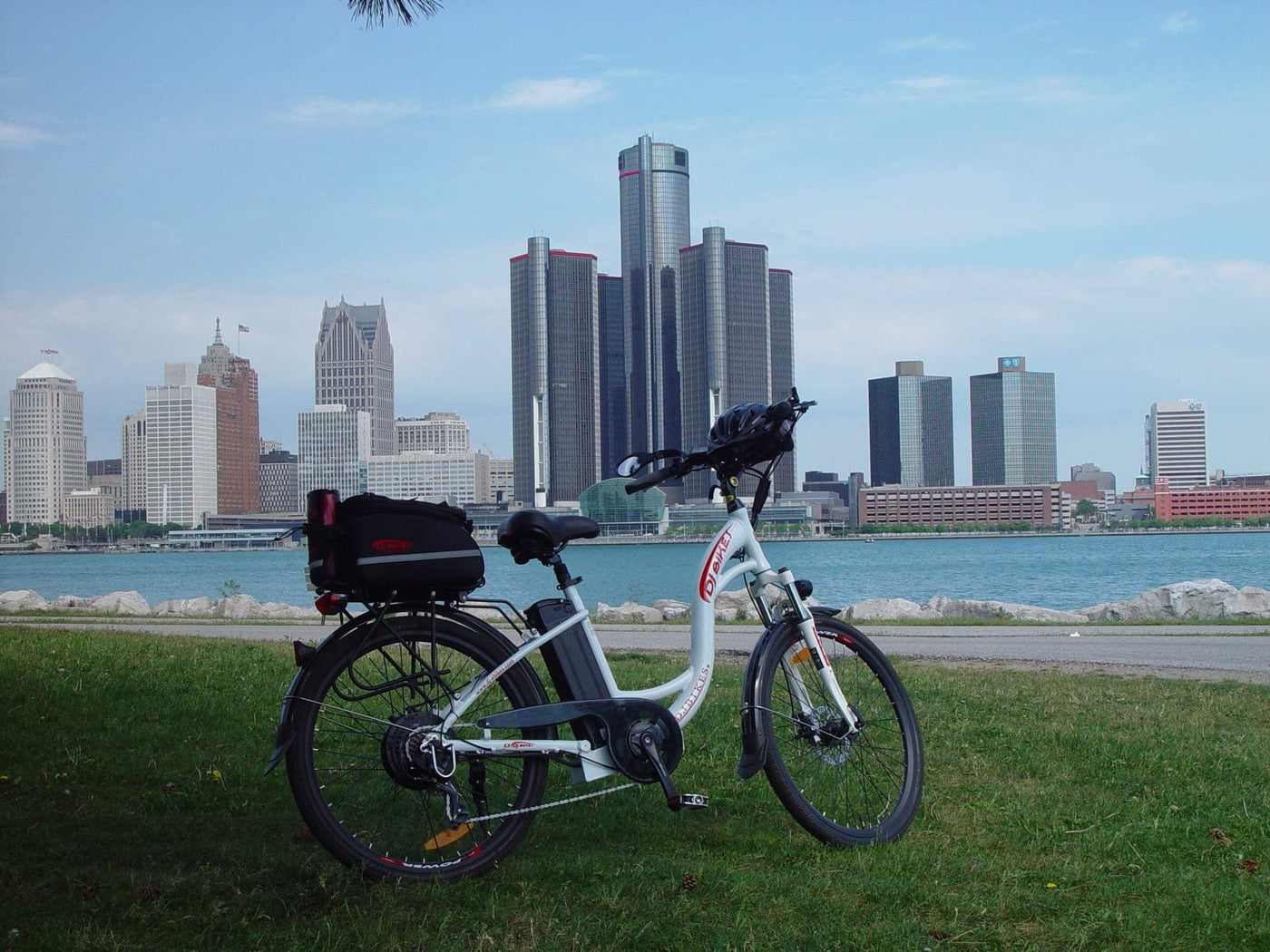 A DJ City Bike e-bike in front of a Detroit skyline and the Detroit River