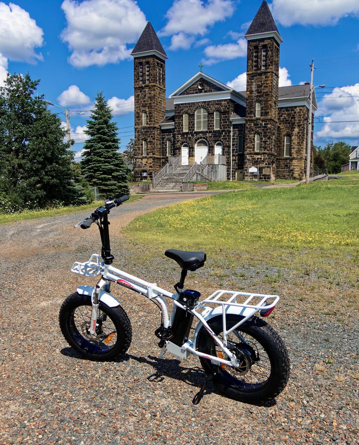 A DJ Folding Bike fat tire e-bike on a gravel road in front of a church